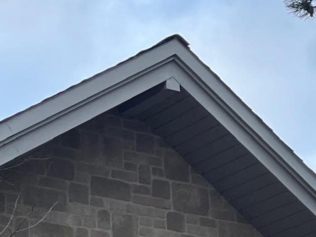 New white fascia and soffit on the gable of a stone house