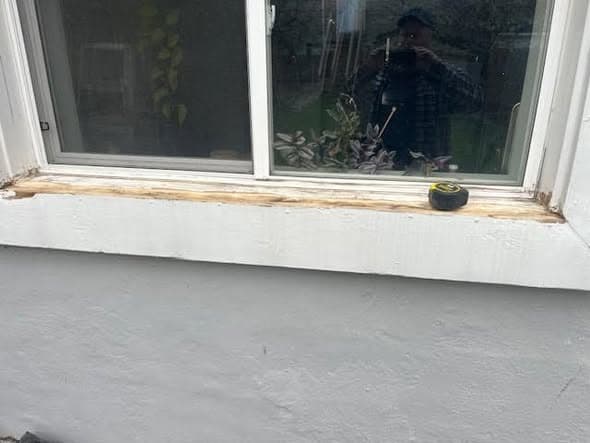 Rotted wooden window sill with a tape measure across it