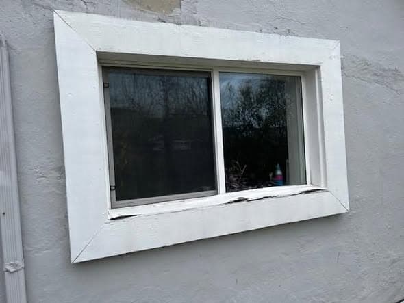 Window with peeling painted wood trim before capping